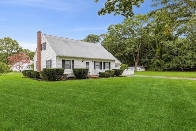 cape cod house with a front yard, roof with shingles, and a chimney