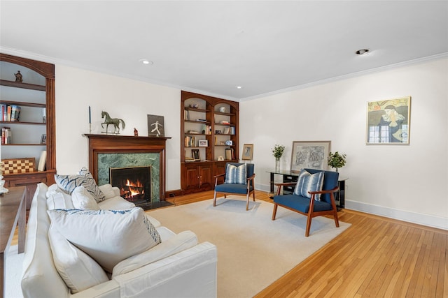 living room featuring ornamental molding, a high end fireplace, built in features, and light hardwood / wood-style floors