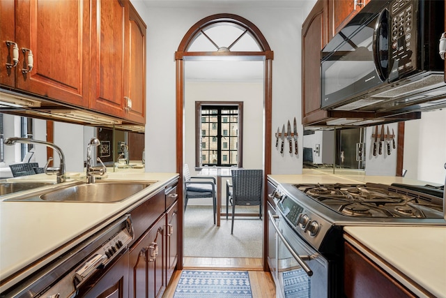 kitchen featuring dishwashing machine, sink, stainless steel gas range, and light hardwood / wood-style floors