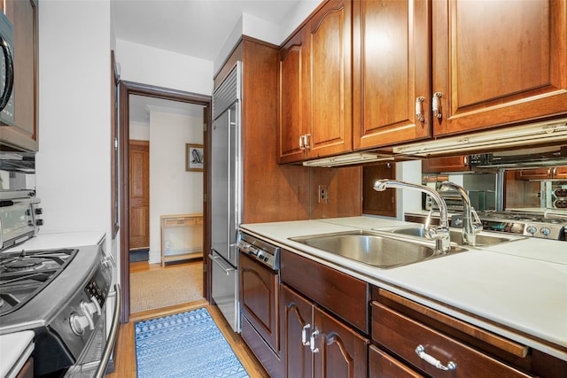 kitchen featuring appliances with stainless steel finishes, sink, and light wood-type flooring