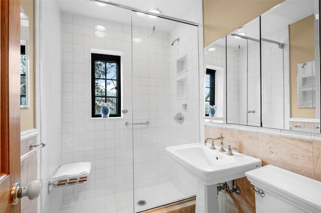 bathroom featuring toilet, an enclosed shower, sink, and tile walls