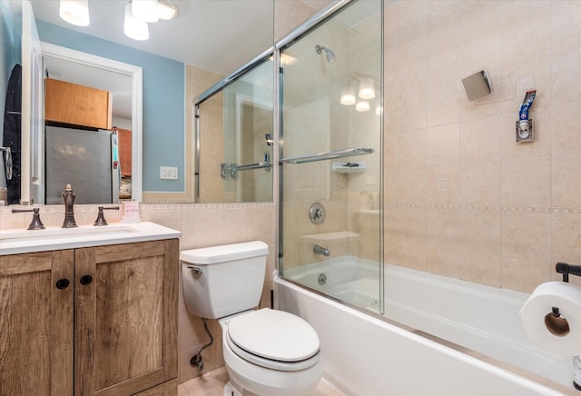 full bathroom featuring vanity, tile walls, shower / bath combination with glass door, and toilet