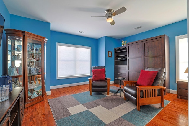 sitting room with ceiling fan and wood-type flooring