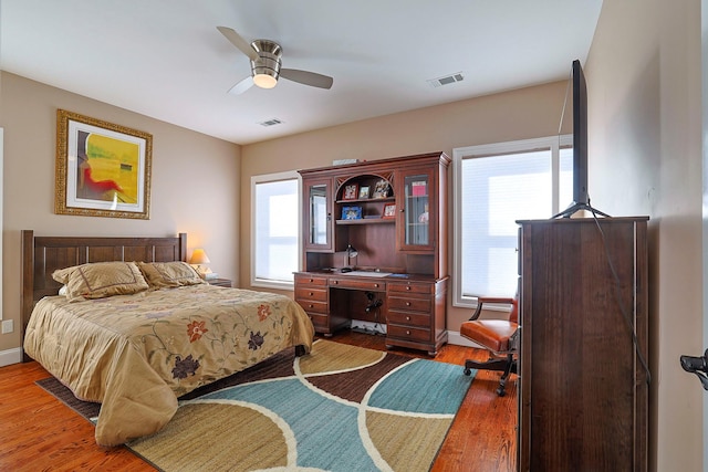 bedroom with multiple windows, dark hardwood / wood-style flooring, and ceiling fan