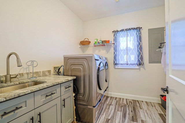 laundry room with washer and dryer, sink, cabinets, and light hardwood / wood-style flooring