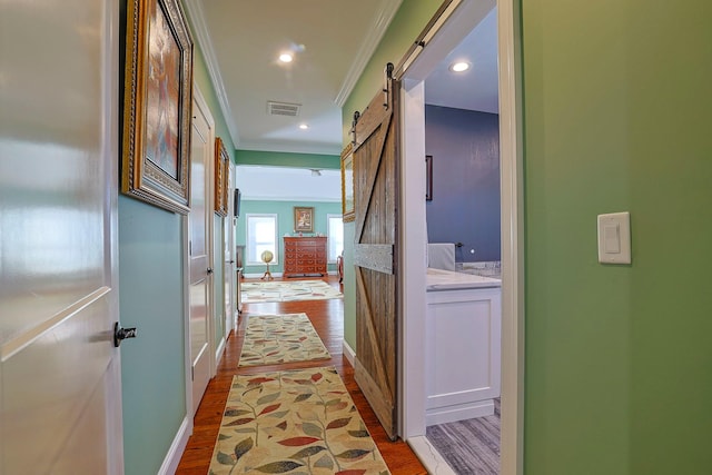 hall featuring hardwood / wood-style flooring, crown molding, and a barn door