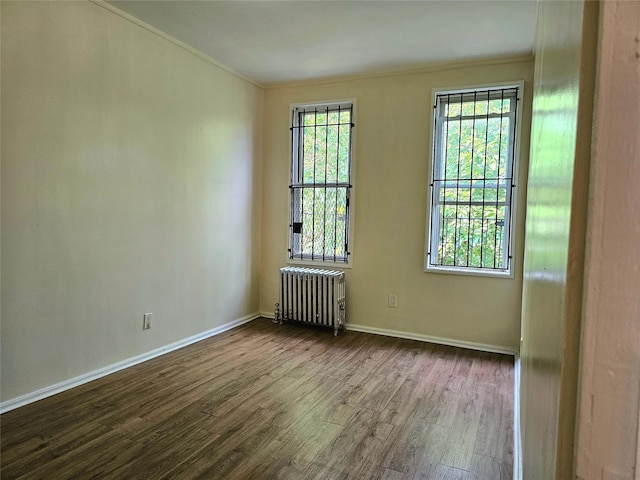 unfurnished room with crown molding, radiator heating unit, and dark hardwood / wood-style floors