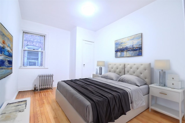 bedroom featuring radiator heating unit and light hardwood / wood-style floors