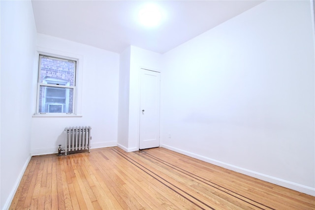 empty room featuring radiator and light hardwood / wood-style flooring