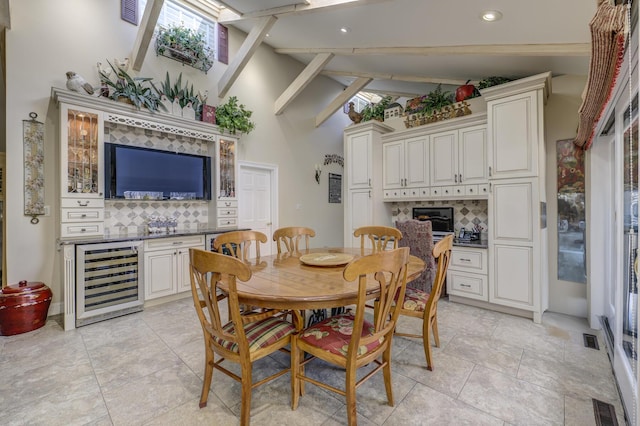 dining area with light tile patterned floors, beam ceiling, high vaulted ceiling, and beverage cooler