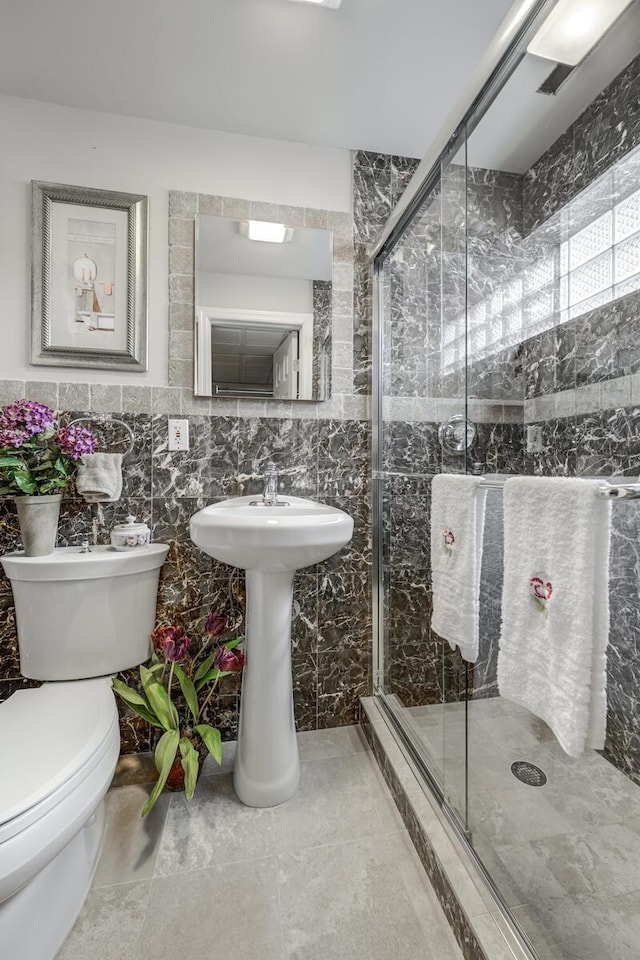 bathroom with a shower with shower door, tile walls, and toilet