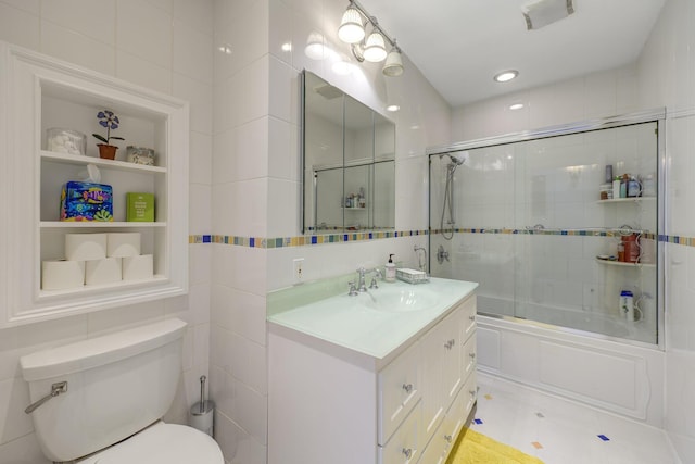 full bathroom with combined bath / shower with glass door, tile walls, vanity, toilet, and built in shelves