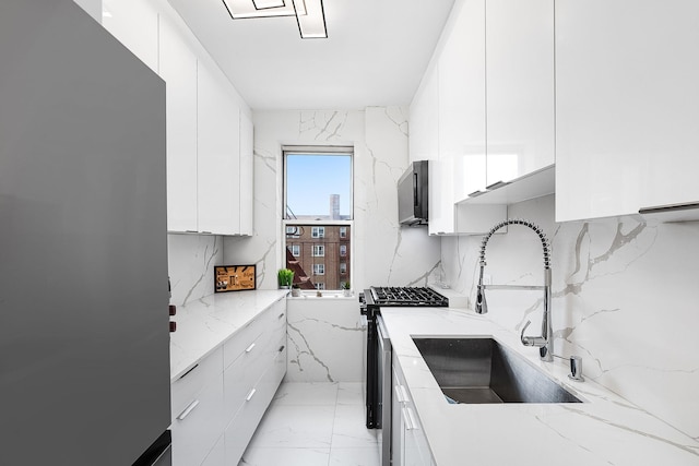 kitchen featuring light stone countertops, appliances with stainless steel finishes, sink, and white cabinets