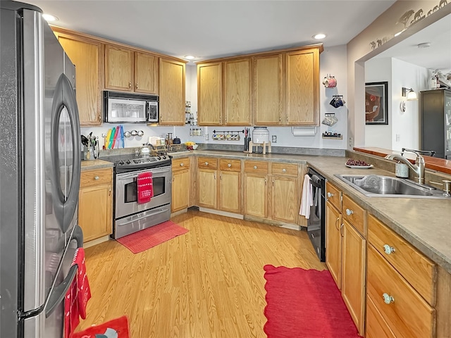 kitchen with sink, stainless steel appliances, kitchen peninsula, and light wood-type flooring