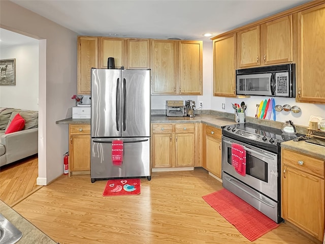 kitchen with appliances with stainless steel finishes and light hardwood / wood-style floors