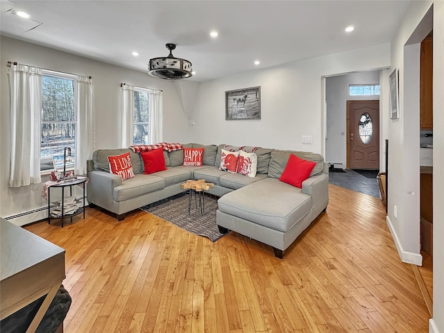 living room with a baseboard heating unit and light wood-type flooring