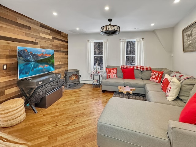 living room featuring light hardwood / wood-style flooring, wooden walls, and a wood stove