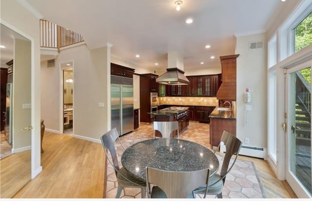 dining area featuring a baseboard radiator, ornamental molding, sink, and light wood-type flooring