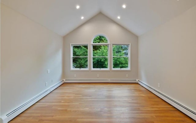 empty room with light wood-type flooring, a baseboard radiator, and vaulted ceiling