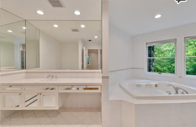 bathroom with vanity and tiled tub