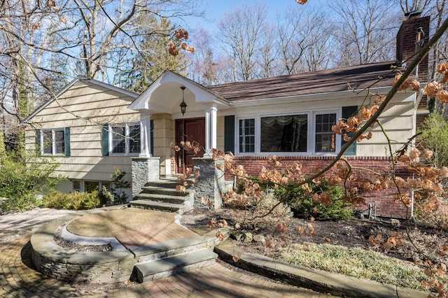 view of front of property with a chimney and brick siding