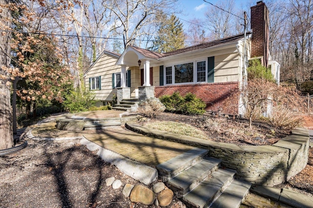 view of front of property featuring a chimney and brick siding