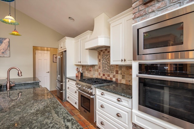 kitchen featuring pendant lighting, custom range hood, white cabinetry, a sink, and high quality appliances