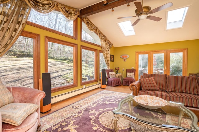 living room featuring ceiling fan, hardwood / wood-style flooring, vaulted ceiling with skylight, and baseboard heating