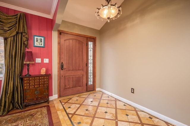 entryway featuring ornamental molding, an inviting chandelier, and baseboards