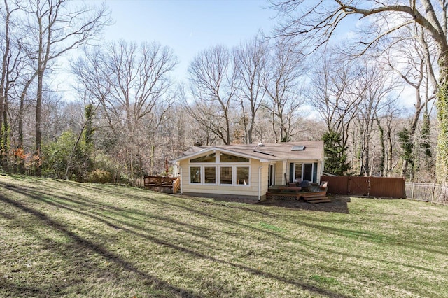 back of property with a lawn and fence