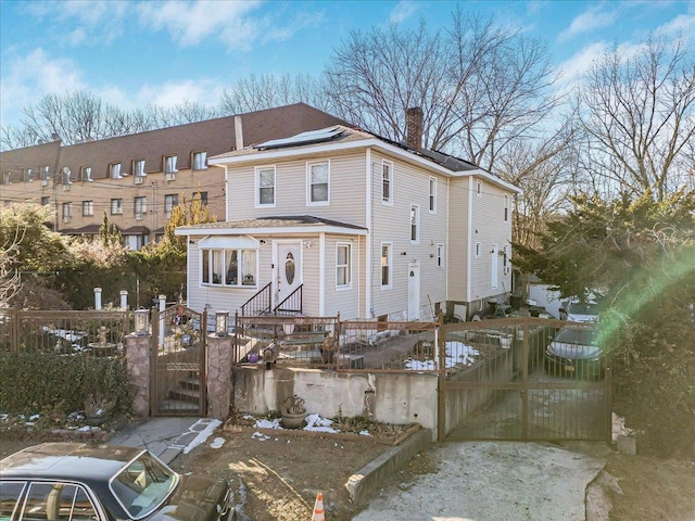 view of front of home with fence, a chimney, and a gate