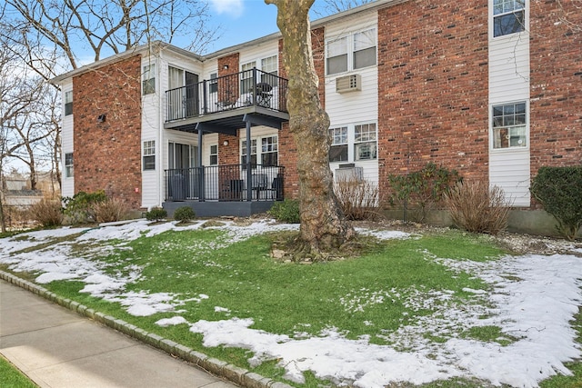 view of front of property with brick siding, a lawn, and a balcony