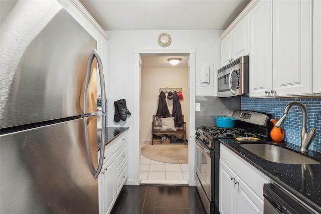 kitchen featuring appliances with stainless steel finishes, white cabinets, a sink, and decorative backsplash