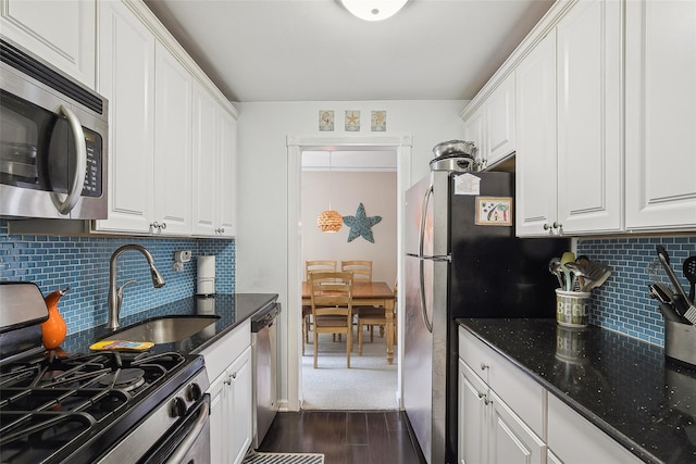 kitchen featuring dark stone counters, stainless steel appliances, dark wood-type flooring, and white cabinetry