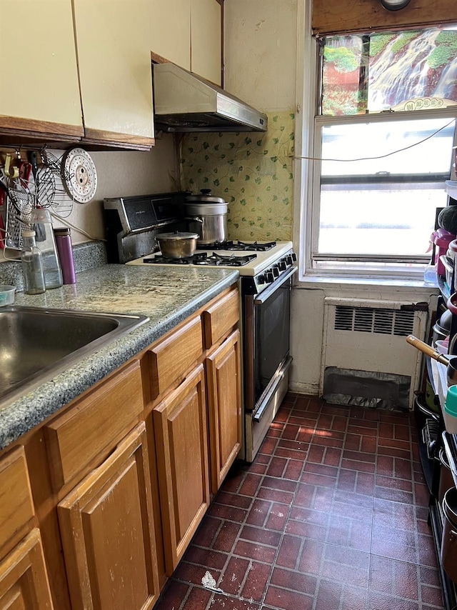 kitchen featuring gas stove, radiator heating unit, and decorative backsplash