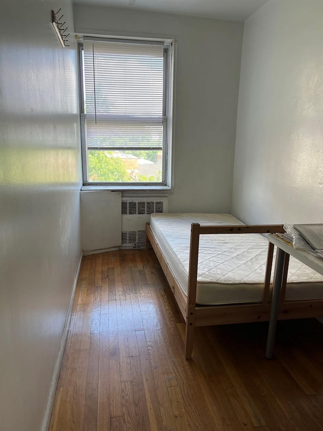 unfurnished bedroom featuring radiator and hardwood / wood-style floors