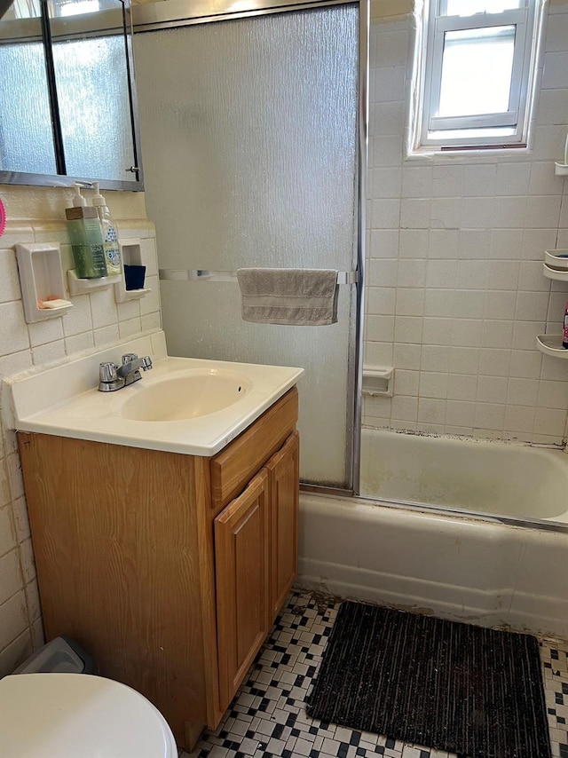 full bathroom featuring combined bath / shower with glass door, tasteful backsplash, tile patterned flooring, vanity, and toilet