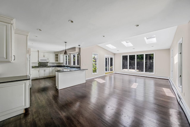 10 Clearbrook Dr, Smithtown, NY 11787 - unfurnished living room with dark wood-style floors, vaulted ceiling, a skylight, baseboards, and a sink