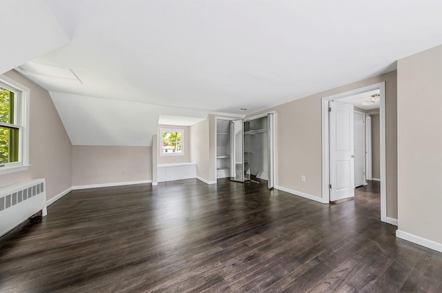 10 Clearbrook Dr, Smithtown, NY 11787 - unfurnished living room with radiator heating unit, healthy amount of natural light, dark wood-type flooring, baseboards, and vaulted ceiling
