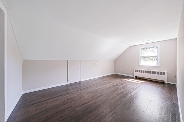 10 Clearbrook Dr, Smithtown, NY 11787 - additional living space with radiator heating unit, dark wood-style flooring, vaulted ceiling, and baseboards