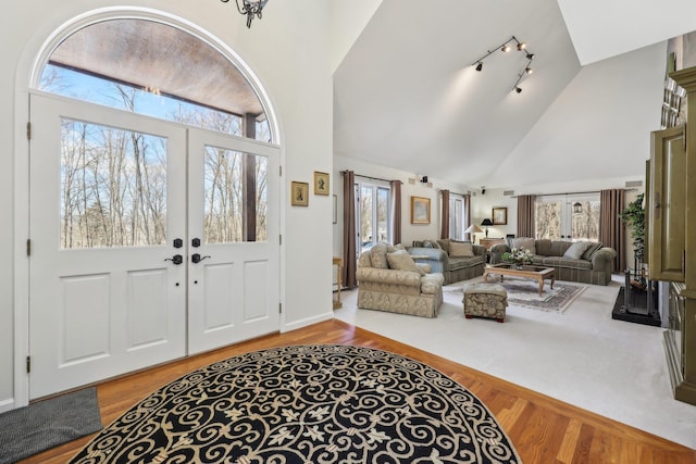 entrance foyer with high vaulted ceiling, track lighting, wood-type flooring, and french doors