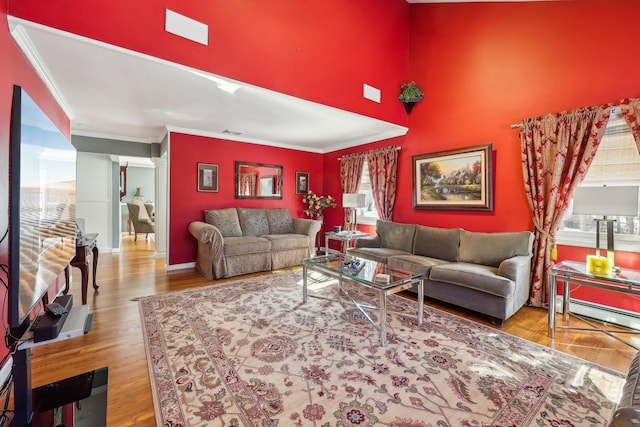 living room with light wood-type flooring, ornamental molding, and a baseboard radiator