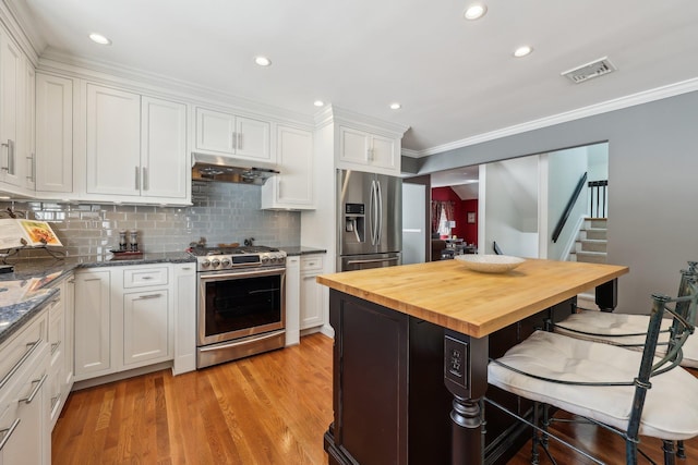 kitchen with light hardwood / wood-style floors, stainless steel appliances, white cabinetry, and wooden counters