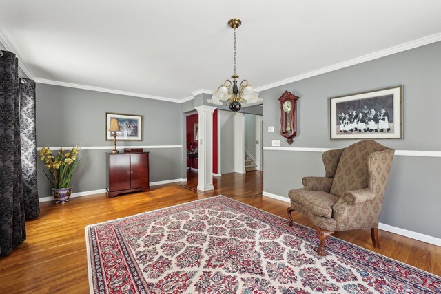 living area with ornamental molding, hardwood / wood-style flooring, and a notable chandelier