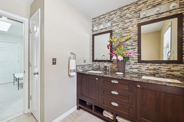 bathroom featuring tile patterned flooring, a skylight, vanity, and decorative backsplash