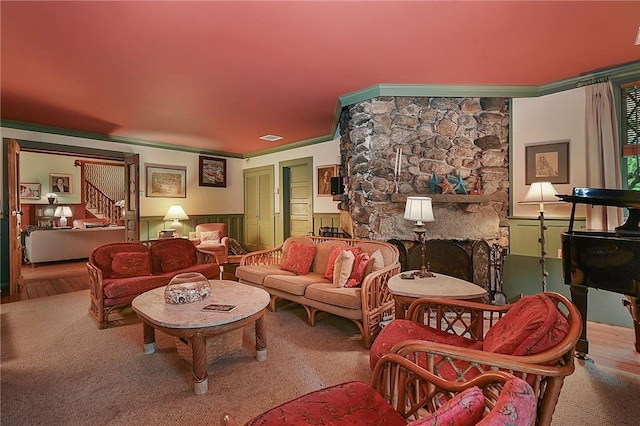 living room with hardwood / wood-style flooring, ornamental molding, and a fireplace