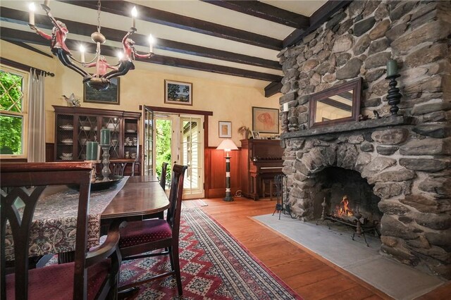 dining area featuring a notable chandelier, beam ceiling, light hardwood / wood-style flooring, and a fireplace