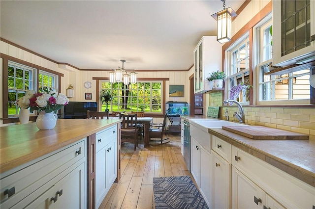 kitchen with pendant lighting, sink, white cabinetry, and crown molding