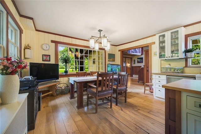 dining area with crown molding, a chandelier, and light wood-type flooring