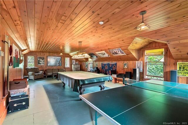 rec room with concrete flooring, pool table, vaulted ceiling, wooden ceiling, and wooden walls